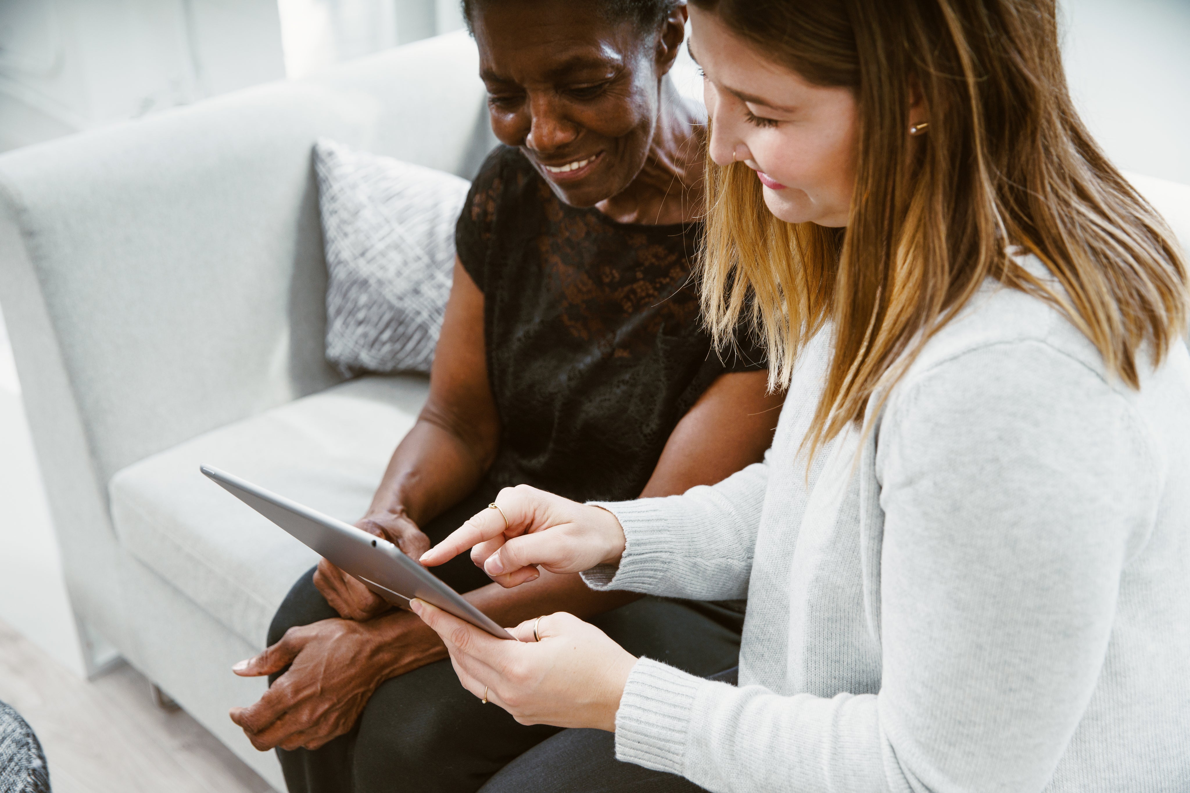 woman guiding a senior woman using an ipad